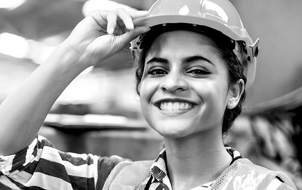 Smiling female worker in hard hat and reflective vest